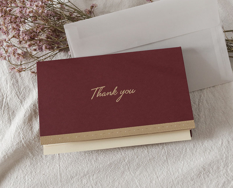 Dark red thank you greeting card + envelope + hand