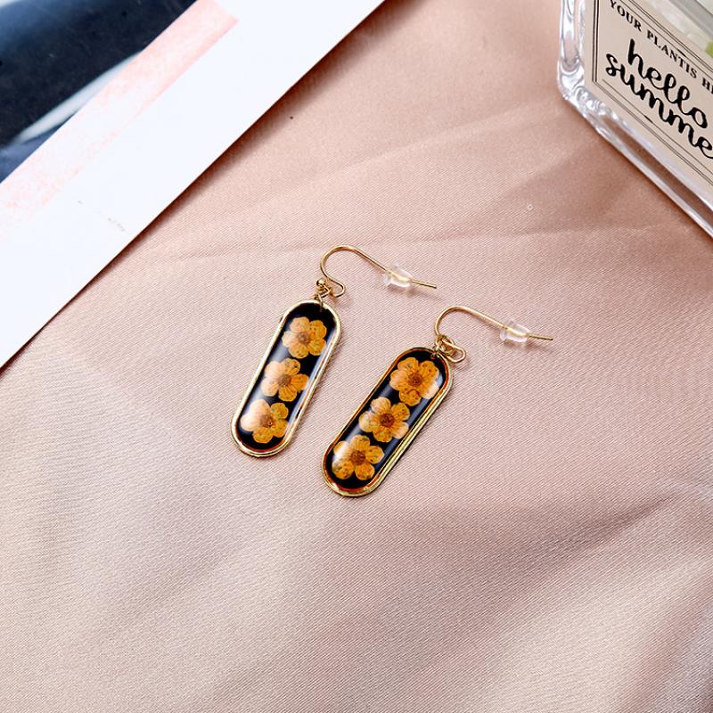 10:11 Daffodil Earrings with a long Square round head on black background