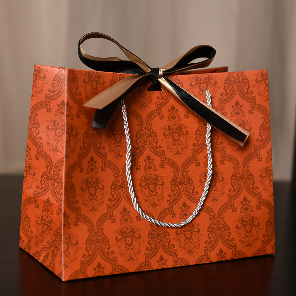 Orange with gold and black ribbon; white cardboard